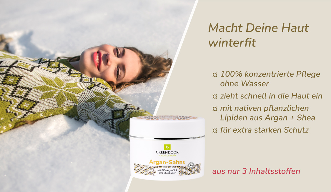 Junge glückliche Frau liegt im Schnee, daneben Greendoor Argansahne plus Aussage Macht Deine Haut winterfit