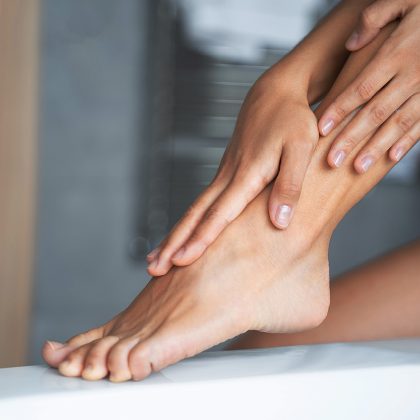 Ein Fuss in Nahaufnahme, der von beiden Händen gestreichelt wird