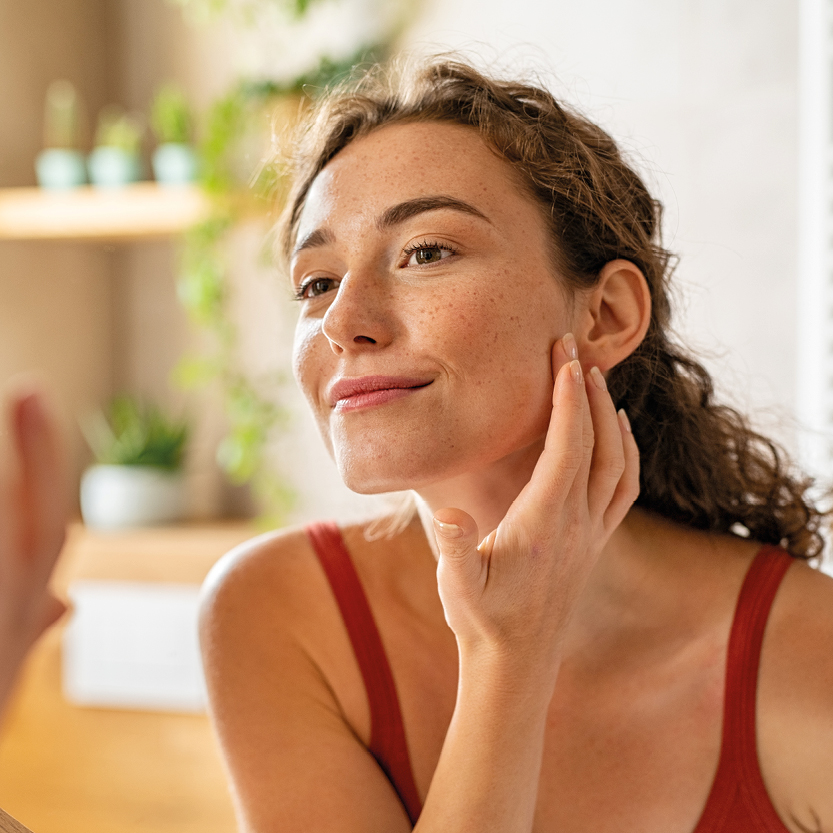 Bildmaterial3 Frau schaut in den Spiegel und betreibt Gesichtspflege
