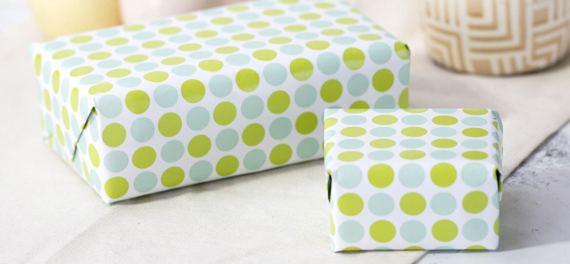 Zwei eingepackte rechteckige Geschenke in Paier mit hellgrünen und hellblauen Punkten