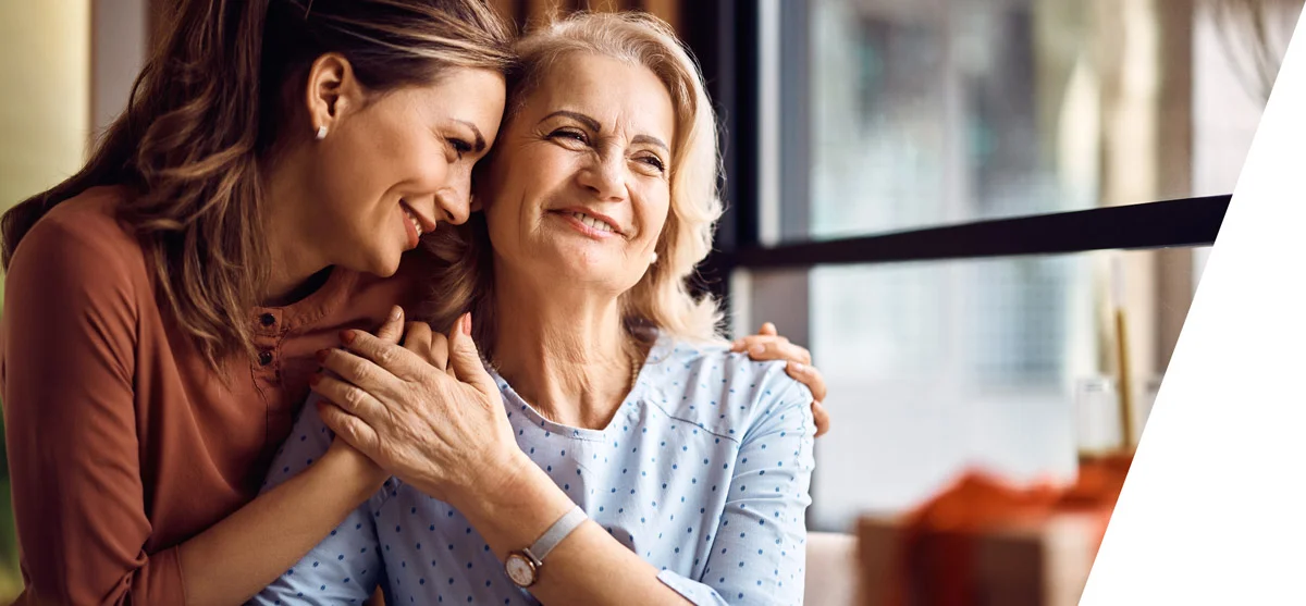 Zwei glückliche Frauen in inniger Umarmung, die ältere Frau ist offensichtlich die Mutter der jüngeren Frau
