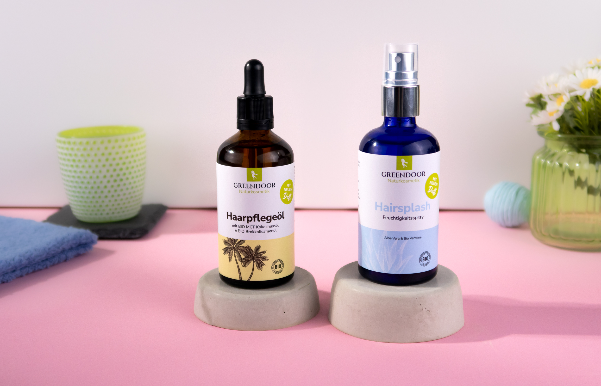 Greendoor Haarpflegeöl und Greendoor Hairsplash in farbigen Galsflschen vor österlichem Hintergrund