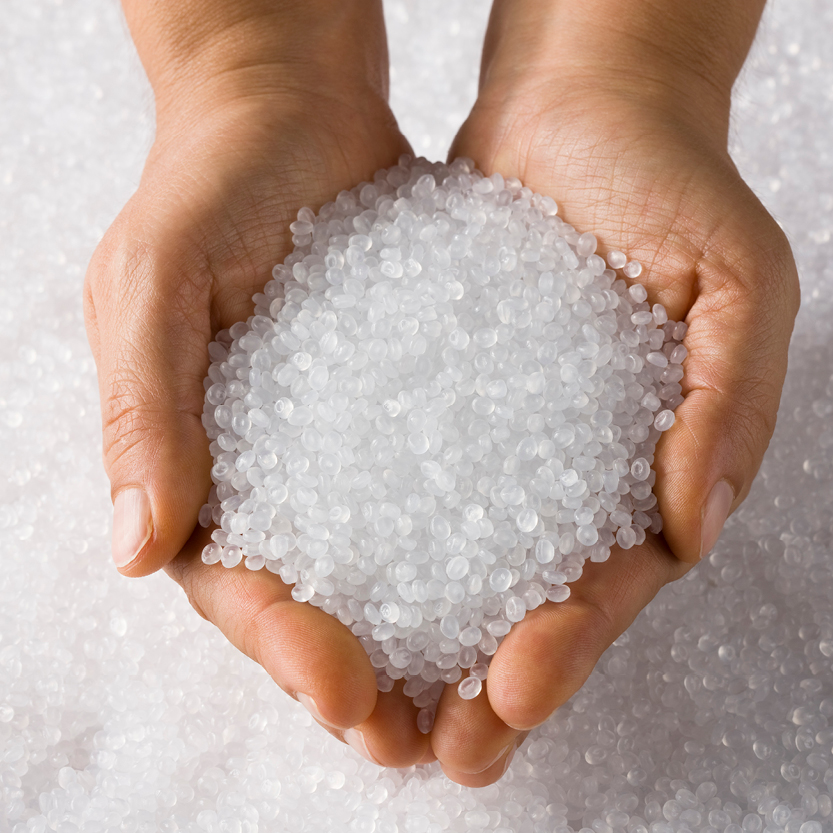 weißes Kunststoffgranulat in zwei menschlichen Händen