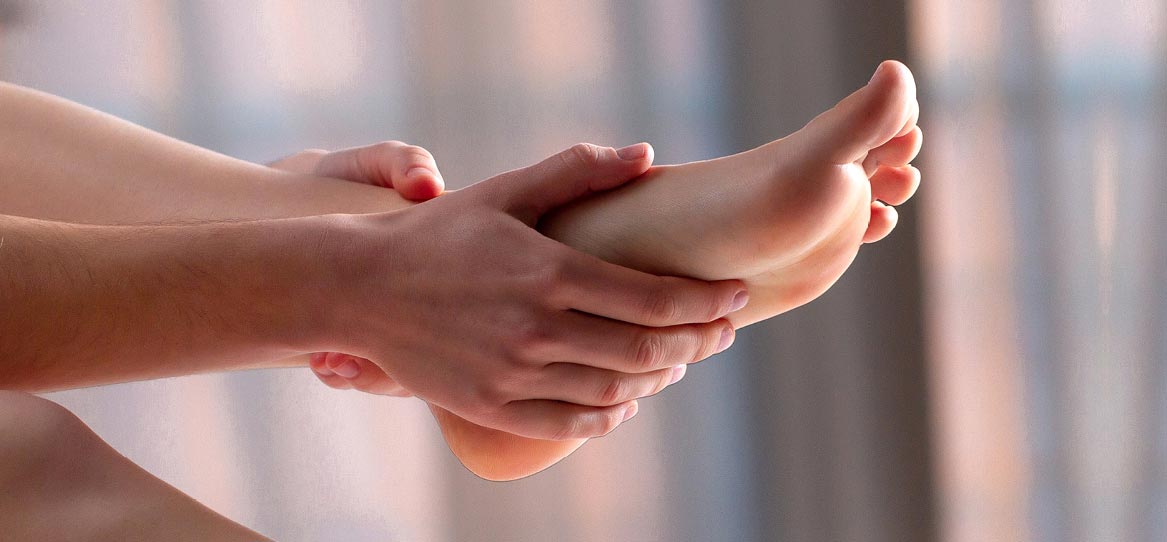 Zwei Hände streichen über einen nackten Fuß