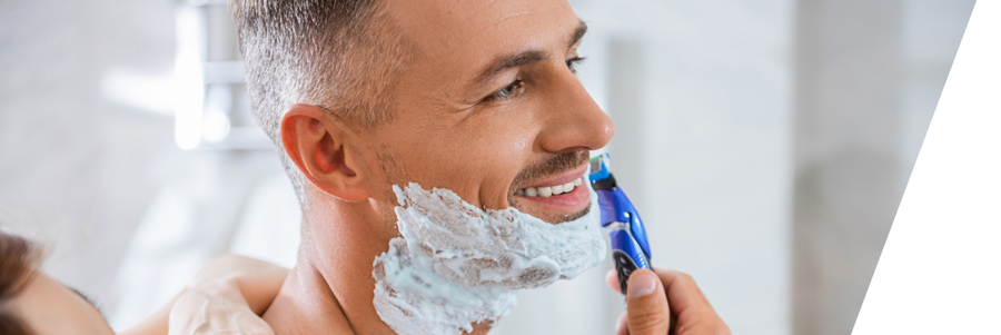 Fröhlicher Mann mittleren Alters bei der Nassrasur mit einem blaun Rasierhobel