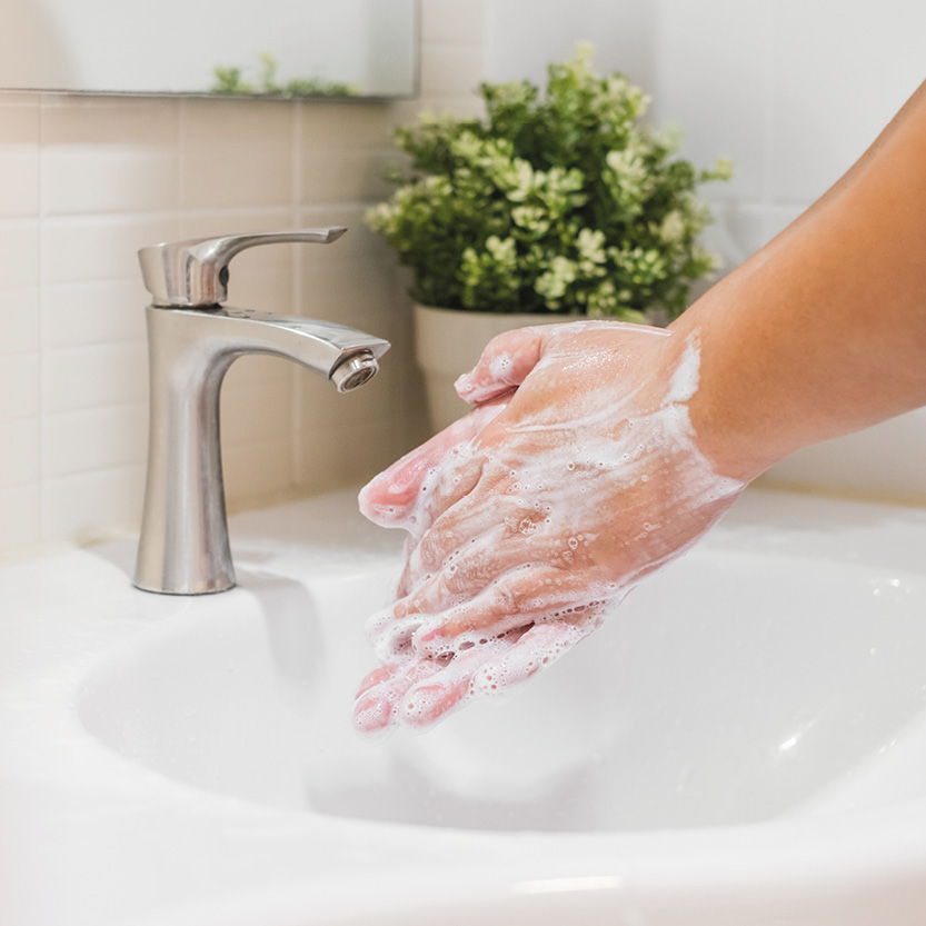 Ein Waschbecken, über dem zwei Hände beim Händewaschen zu sehen sind