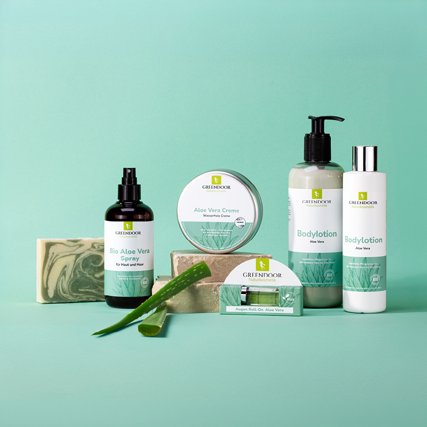 Es sind verschiedene Greendoor Aloe Vera Produkte zu sehen: Aloe Vera Spray, Aloe Vera Creme, Aloe Vera Roll On und Aloe Vera Bodylotion in zwei Flaschengrößen
